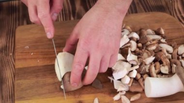 Erkek eli, tahta tahtalarda istiridye mantarı dilimlerini kesiyor.