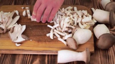 Erkek eller tahta tahtalarda istiridye mantarlarının küçük parçalarını kesiyor.