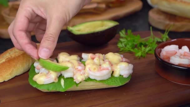Mão masculina preparando sanduíche de baguete com peões, abacate, salada, molho de perto — Vídeo de Stock