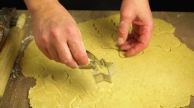 Erkek elleri hamurdan Noel kurabiyesi kesiyor, 4K yakın plan.