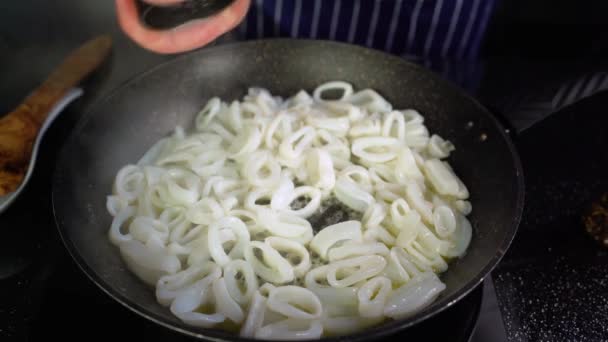 Chef masculino agregando sal en el anillo de calamar frito en una especia de calamares de sartén, vista superior 4K — Vídeo de stock