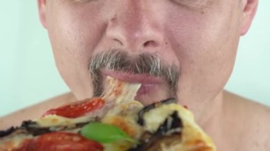 Orta yaşlı, sakallı, vejetaryen pizzası yiyen bir adam.