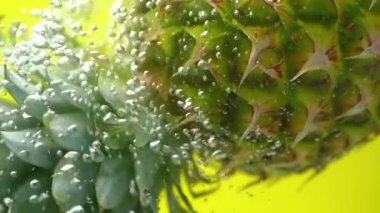 Sarı arka planda baloncukları olan ananas kopyalama alanı yavaş çekim düşen su