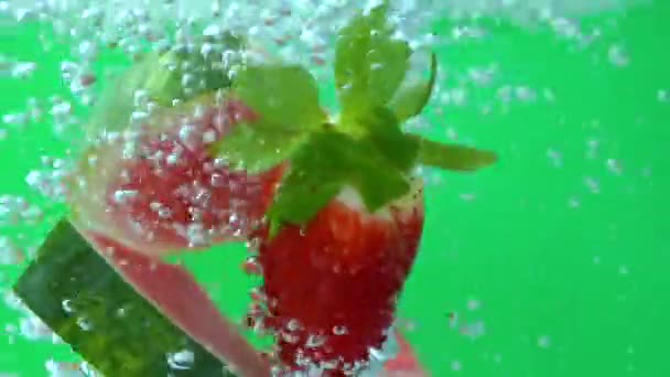 Vallende aardbeien en watermeloen in waterglas, spatbelletjes, close-up — Stockvideo