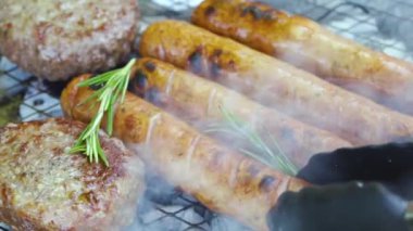 Kömürde kızartılmış biberiyeli barbekü ve sosis, ızgarada çiğ et.