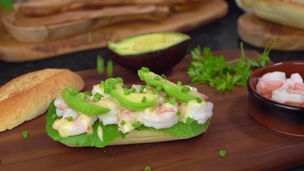 Falling parsley on baguette sandwich with pawns, avocado, cheese sauce, close up — Stok Video