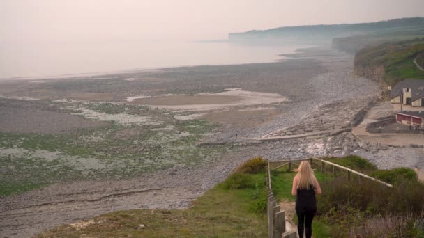 Молодая женщина заниматься спортом, бег на скалистом берегу моря фоне, 4K — стоковое видео