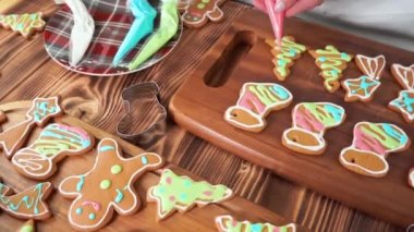 Noel zencefilli ekmek, renkli kremalı şeker, kadın elleri pasta topluyor.