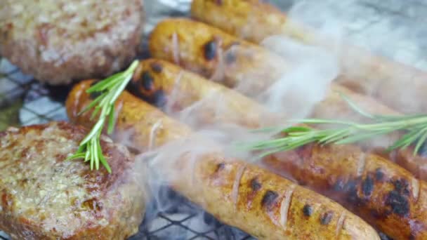 Kotlety i kiełbaski z rozmarynem smażone na węglu, surowe mięso na grillu — Wideo stockowe
