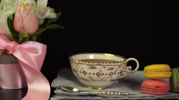 Skład filiżanki herbaty, makaroniki, bukiet kwiatów, tło uroczystości — Wideo stockowe