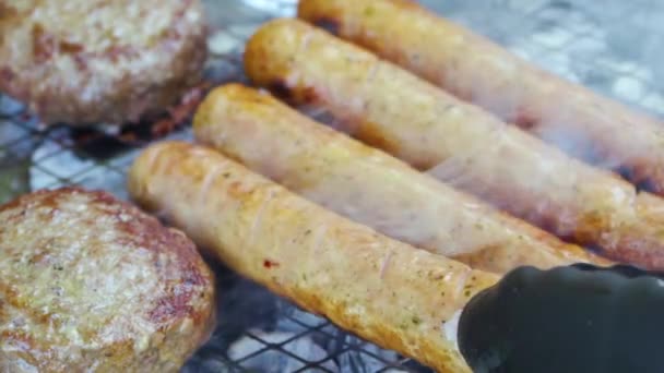 Carne cruda a la parrilla, chuletas de barbacoa y salchichas a base de hierbas y especias fritas sobre carbones — Vídeos de Stock