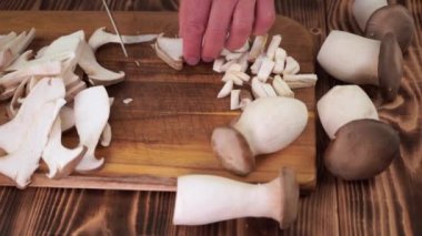 Erkek eller tahta tahtalarda istiridye mantarlarının küçük parçalarını kesiyor.