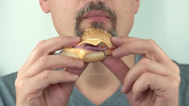 Aç orta yaşlı adam aç gözlülükle vejetaryen hamburgerini yiyor. — Stok video