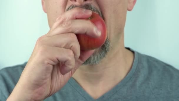 髭を生やした中年男性が手で保持し、健康的な赤いリンゴを食べます,閉じる4K — ストック動画