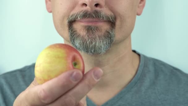 髭を生やした中年男性が手で保持し、健康的な赤いリンゴを食べます,閉じる4K — ストック動画
