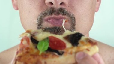 Orta yaşlı, sakallı, vejetaryen pizzası yiyen bir adam.