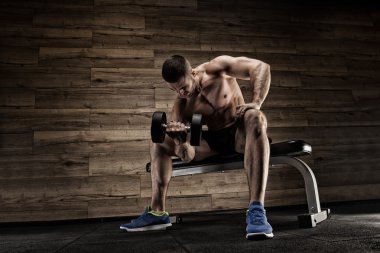 Yakışıklı ve kaslı bir adam, spor salonunda kameraya poz veriyor.