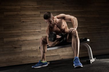 Yakışıklı ve kaslı bir adam, spor salonunda kameraya poz veriyor.