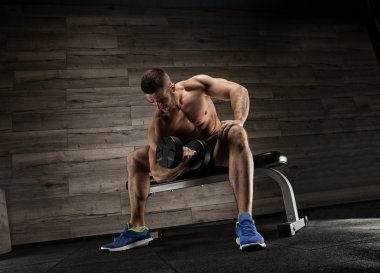 Yakışıklı ve kaslı bir adam, spor salonunda kameraya poz veriyor.