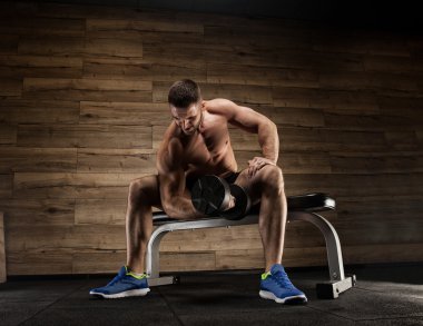 Yakışıklı ve kaslı bir adam, spor salonunda kameraya poz veriyor.