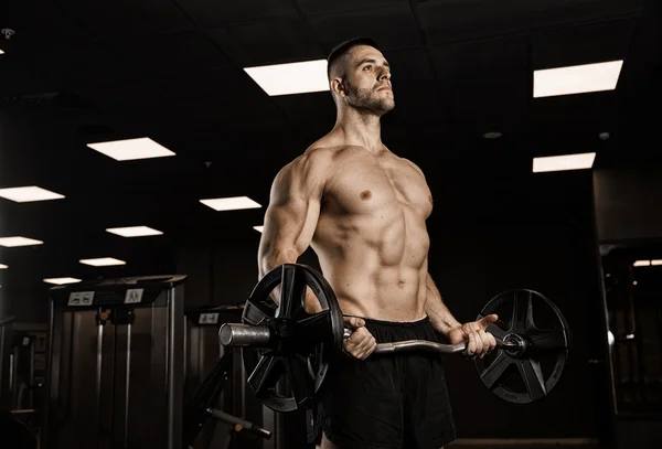 Όμορφος άντρας με μεγάλους μυς, ποζάρει στην κάμερα του γυμναστηρίου. — Φωτογραφία Αρχείου