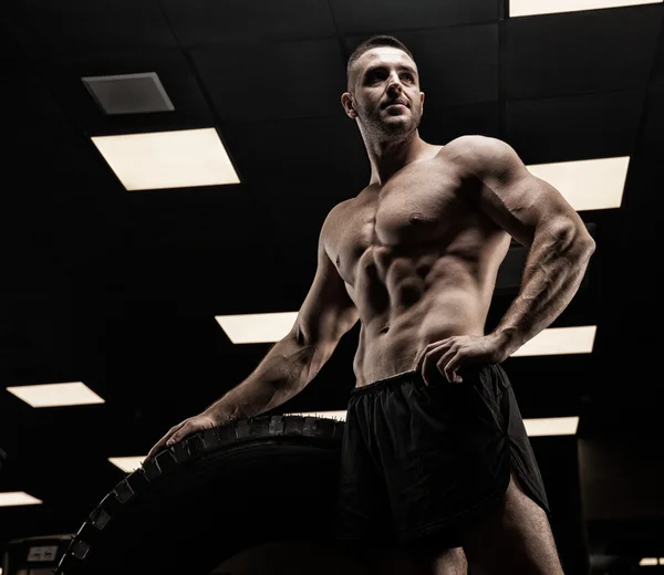 Pohledný muž s velkými svaly, pózující na kameru v tělocvičně — Stock fotografie