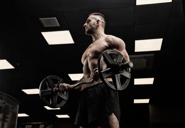 Hombre guapo con grandes músculos, posando en la cámara en el gimnasio — Foto de Stock