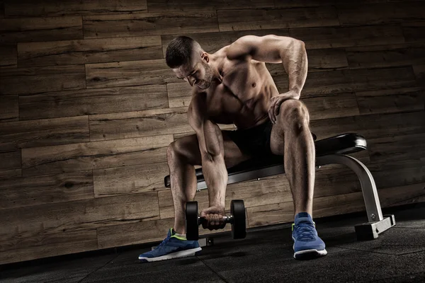 Yakışıklı ve kaslı bir adam, spor salonunda kameraya poz veriyor.