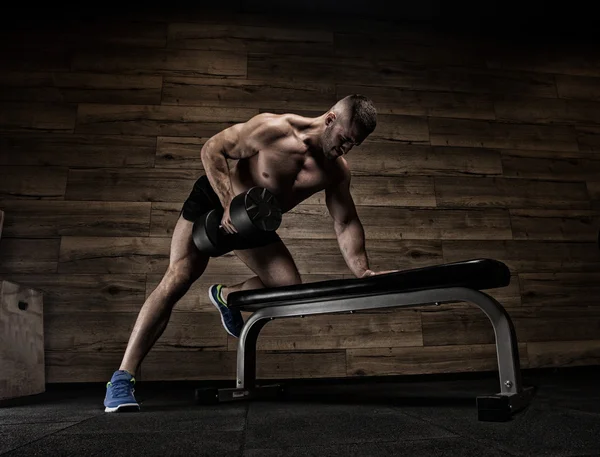 Yakışıklı ve kaslı bir adam, spor salonunda kameraya poz veriyor. — Stok fotoğraf