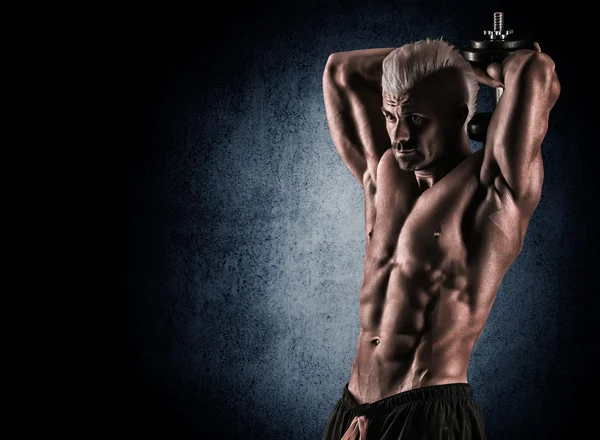 Portrait of a handsome muscular bodybuilder posing over black ba — Stock Photo, Image