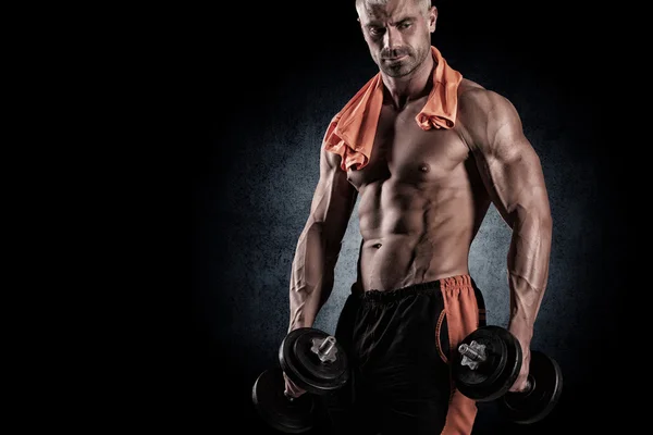 Muscular bodybuilder guy doing exercises with dumbbells over bla — Stock Photo, Image