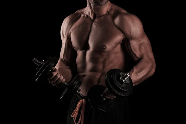 Muscular male athlete is training by lifting dumbbells — Stock Photo, Image