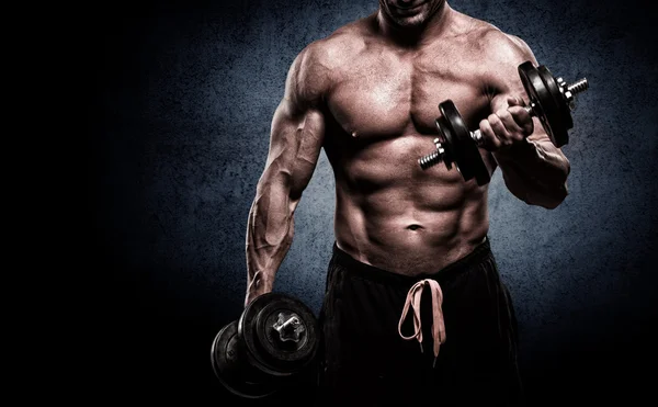 Nahaufnahme eines muskulösen jungen Mannes, der Gewichte auf dunklem Hintergrund stemmt lizenzfreie Stockbilder