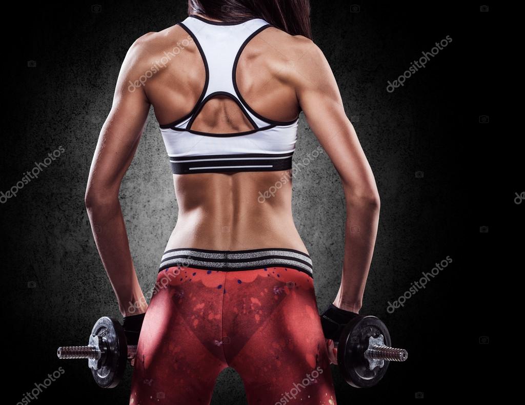 Fitness sexy woman on a sportswear in training pumping up muscle