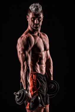 muscular young man lifting weights on dark background clipart