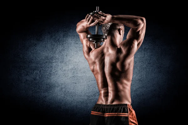 Muscular man raising behind his head dumbbells — Stock Photo, Image