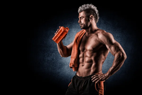 Ung vuxen man dricka proteinshake i gymmet. svart bakgrund. — Stockfoto