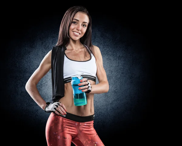 Vacker ung atletisk flicka med en flaska på en vit bak — Stockfoto