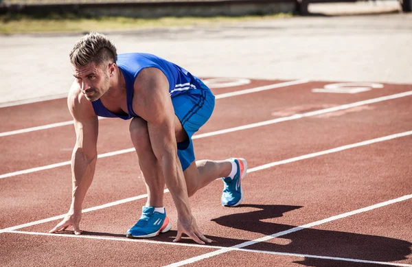 Joven atleta muscular está en el inicio de la cinta de correr en el s —  Fotos de Stock