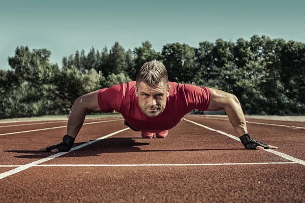 Cross-training tijdens zonsondergang. jonge man doet push ups. — Stockfoto