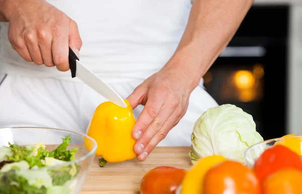 Snygg man som lagar sallad hemma i köket. — Stockfoto