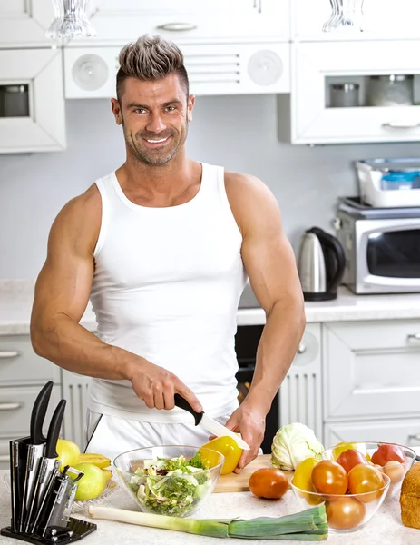 Snygg man som lagar sallad hemma i köket. — Stockfoto