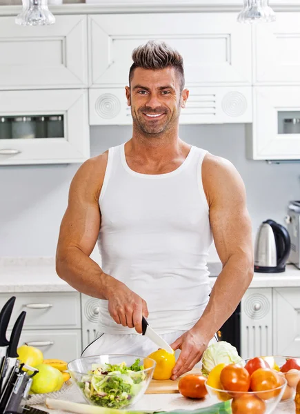 Snygg man som lagar sallad hemma i köket. — Stockfoto