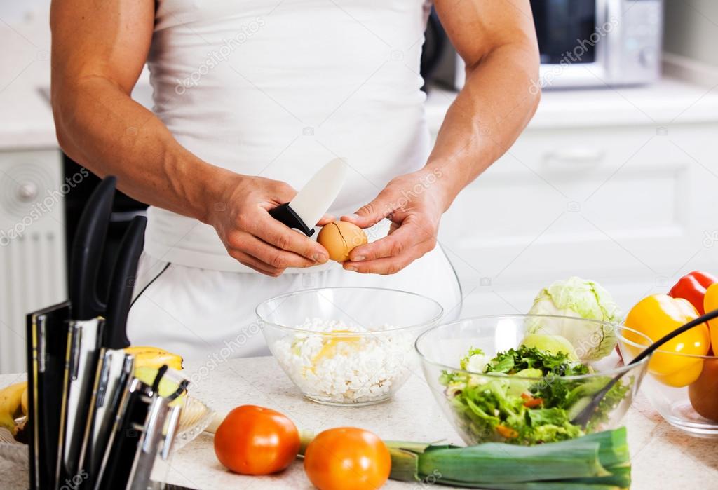 Handsome man cooking at home preparing salad in kitchen.