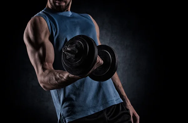 Young man with dumbbell flexing muscles over gray background — 스톡 사진