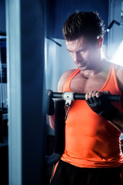 Spor salonunda ağırlık kaldıran genç bir vücut geliştirici..