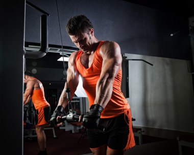 Spor salonunda ağırlık kaldıran genç bir vücut geliştirici..