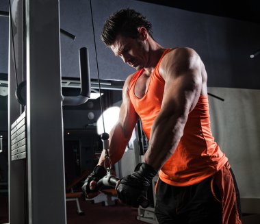 Spor salonunda ağırlık kaldıran genç bir vücut geliştirici..