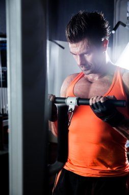 Spor salonunda ağırlık kaldıran genç bir vücut geliştirici..