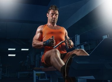 Spor salonunda ağırlık kaldıran genç bir vücut geliştirici..